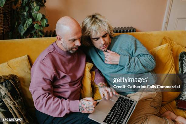 a gay couple use a laptop to shop online - credit union fotografías e imágenes de stock