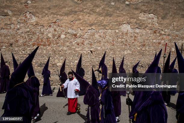 Child holds incense next to penitents from the 'Nuestro Padre Jesus Nazareno' brotherhood during 'Las Caidas' procession on Good Friday on April 15,...