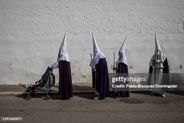 Penitent from the 'Santa Mujer Veronica' brotherhood pushes a baby stroller amid other penitents during 'Las Caidas' procession on Good Friday on...