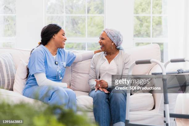 hospice nurse sits and talks with her cancer patient - home carer 個照片及圖片檔