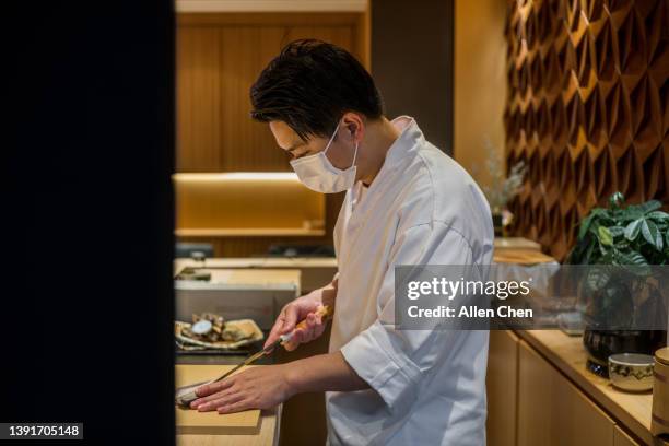 the chef of japanese food makes sushi at the sushi bar - sushi restaurant stock pictures, royalty-free photos & images