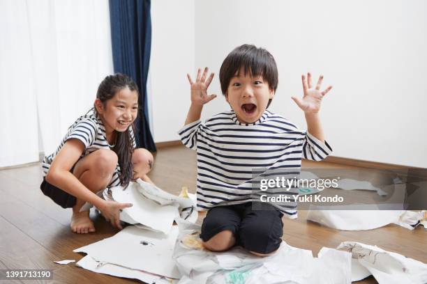 a sister and brother laughing in a messy room. - male preschooler stock pictures, royalty-free photos & images