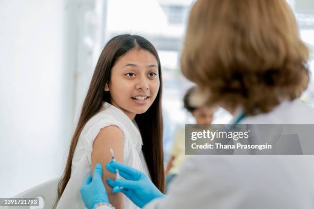 nurse gives students a vaccination in school during coronavirus pandemic - social distancing school stock pictures, royalty-free photos & images