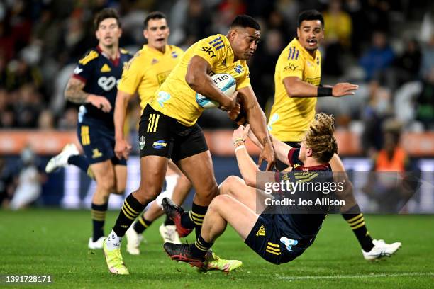 Julian Savea of the Hurricanes charges over Scott Gregory of the Highlanders during the round nine Super Rugby Pacific match between the Highlanders...