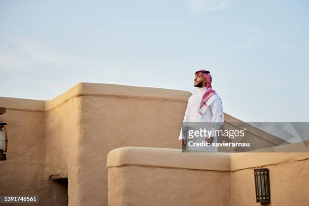 mittlerer erwachsener saudischer mann, der im freien inmitten der ruinen von at-turaif steht - suadi arabia stock-fotos und bilder