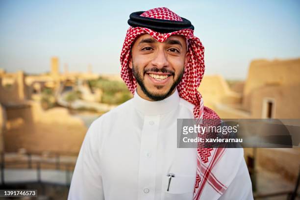 portrait of cheerful saudi man visiting at-turaif ruins - 包頭巾 個照片及圖片檔