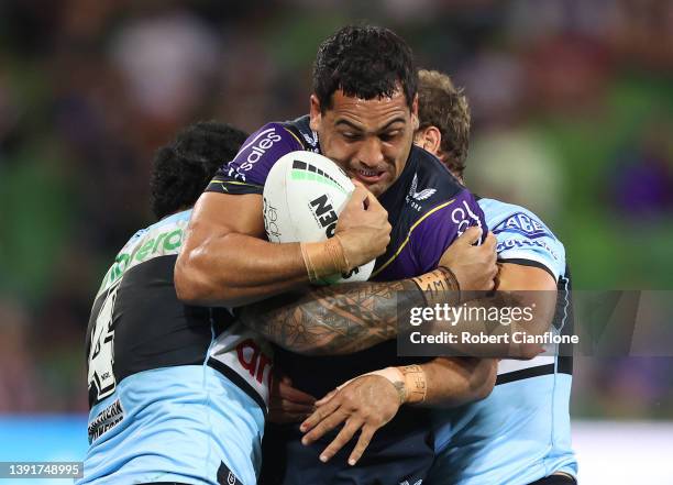 Reimis Smith of the Storm is challenged by Siosifa Talakai and Matt Moylan of the Sharks during the round six NRL match between the Melbourne Storm...