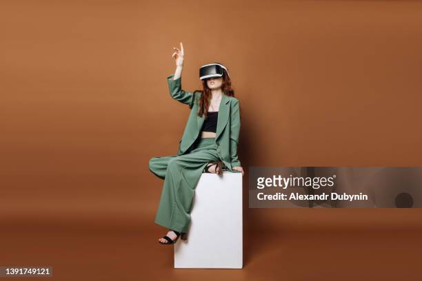 a woman in vertacular reality glasses sits and plays games on a colored background. concept technology and vertical reality. - hi tech moda - fotografias e filmes do acervo