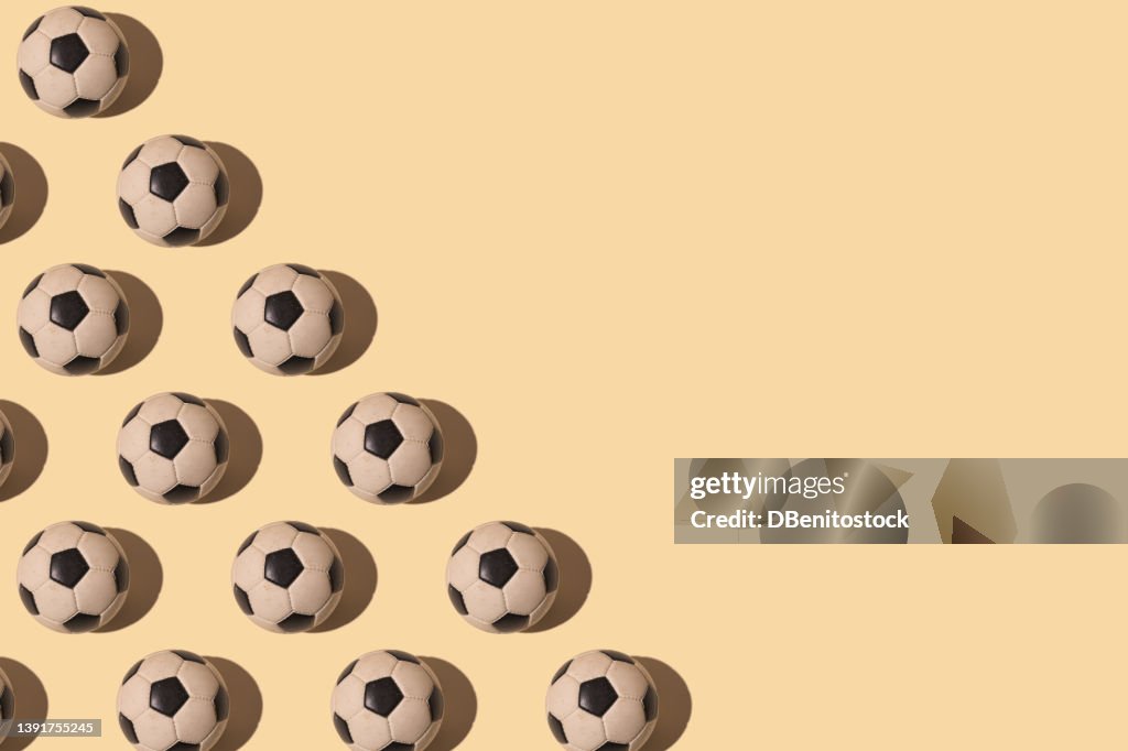 Retro soccer balls pattern with hard shadow, on the left side, on pastel background. Concept of soccer world cup, sport, competition and world champion.