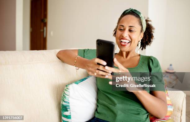 laughing young woman video call with a friend on her smart phone - friends laughing at iphone video stock pictures, royalty-free photos & images