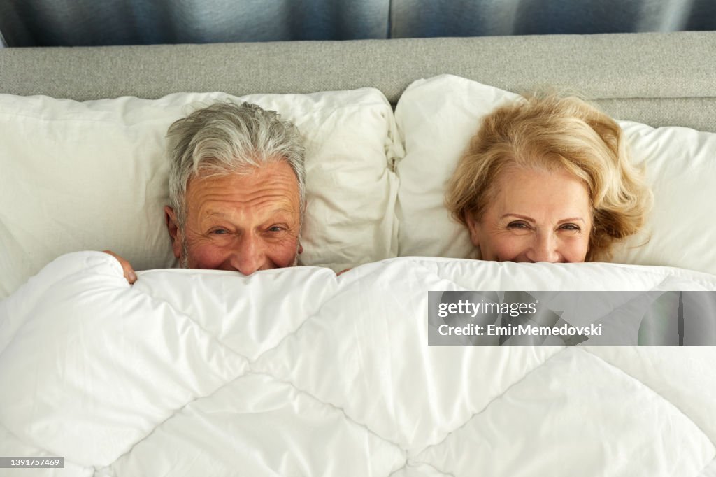 Senior Paar entspannen im Bett versteckt unter Bettwäsche