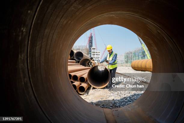 a female engineer used a measuring instrument to measure the quality of steel pipe - pipeline stockfoto's en -beelden