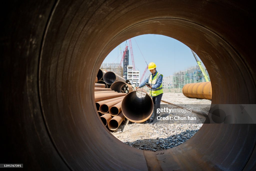 A female engineer used a measuring instrument to measure the quality of steel pipe