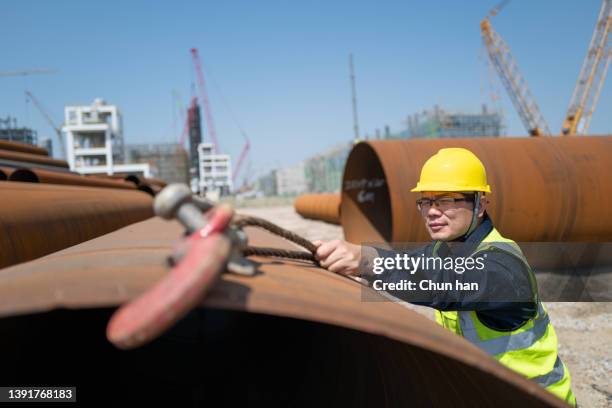 a middle-aged asian male worker on the construction site - lifting heavy objects stock pictures, royalty-free photos & images