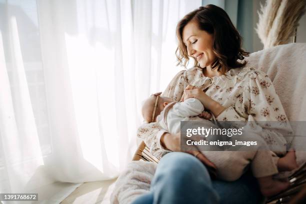 bonita joven madre con niña en casa - amamantar fotografías e imágenes de stock