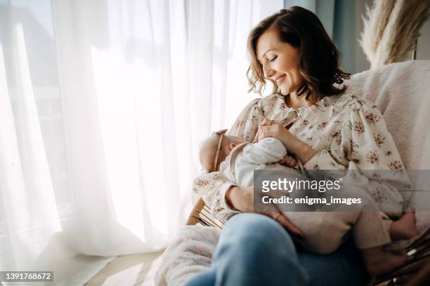 simpatica giovane madre con bambina a casa - attrezzatura per neonato foto e immagini stock