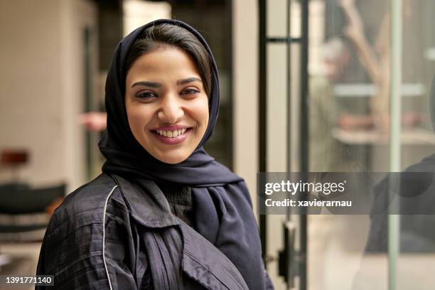 portrait intérieur d’une femme saoudienne joyeuse au milieu des années 20 - femme foulard photos et images de collection