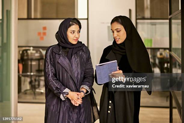 young saudi businesswomen discussing plans in modern office - saudi women stock pictures, royalty-free photos & images