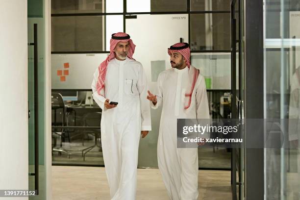 hombres de negocios sauditas caminando y hablando en una oficina moderna - arabia saudí fotografías e imágenes de stock