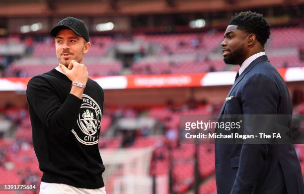 Jack Grealish of Manchester City speaks with pundit and former footballer, Micah Richards prior to The Emirates FA Cup Semi-Final match between...