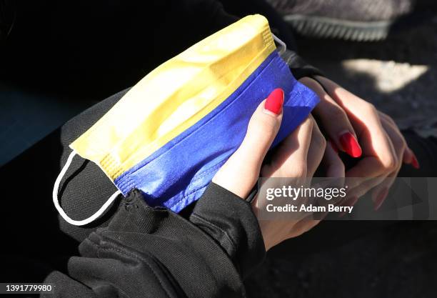 Russian activists Polina Oleinikova holds a Ukrainian flag medical face mask as she participates in a hunger strike outside the Russian embassy...