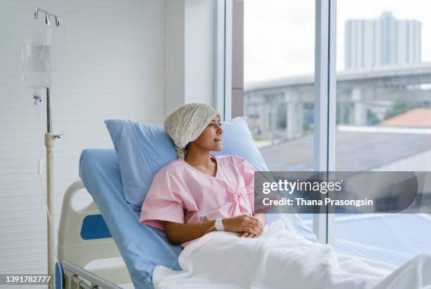 smiling girl with cancer looks out window - child cancer stock pictures, royalty-free photos & images