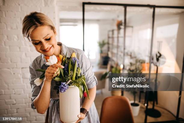 young woman arranging tulips at home - arranging tulips stock pictures, royalty-free photos & images