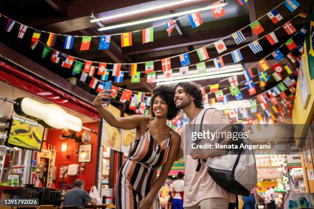 portrait of beautiful tourist couple making selfie in the municipal market - municipal market of sao paulo stockfoto's en -beelden