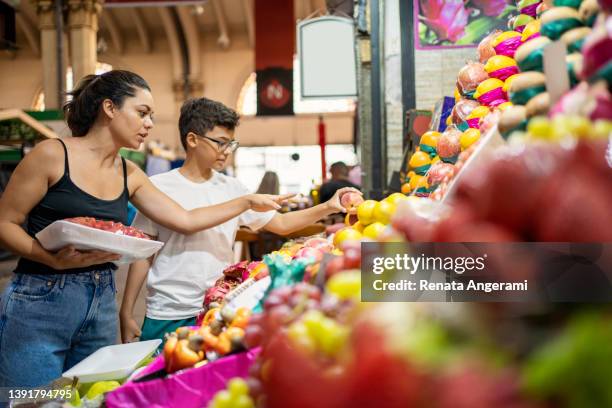 mother and son buying fruits at the municipal market - food market stockfoto's en -beelden