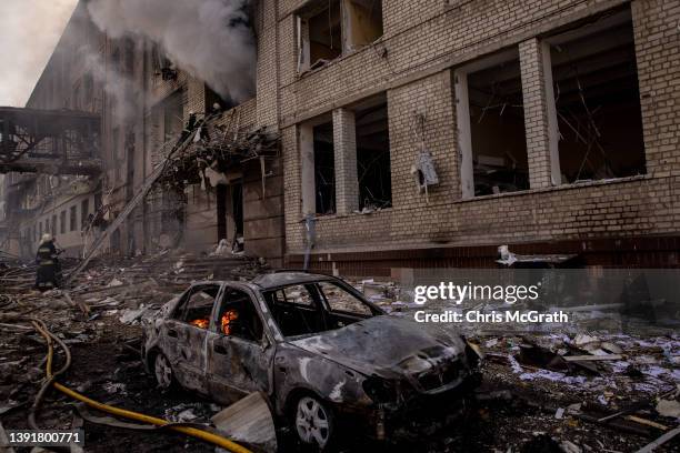 Firefighters work to extinguish a fire at a shopping center and surrounding buildings after a Russian missile strike on April 16, 2022 in Kharkiv,...