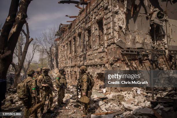 Members of the Ukrainian military walk amid debris after a shopping center and surrounding buildings were hit by a Russian missile strike on April...