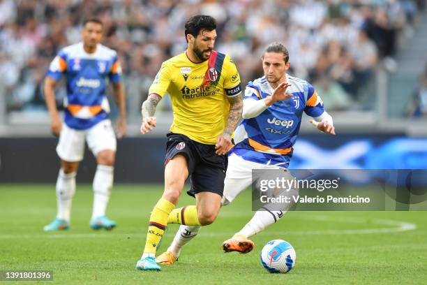 Roberto Soriano of Bologna is marked by juv25during the Serie A match between Juventus and Bologna FC at Allianz Stadium on April 16, 2022 in Turin,...