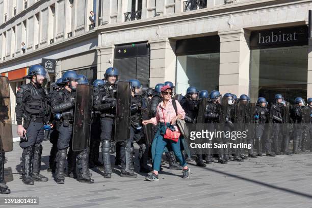 Bystander walks past a police line as protesters demonstrate against the rise of the far-right in French politics, on April 16, 2022 in Paris,...