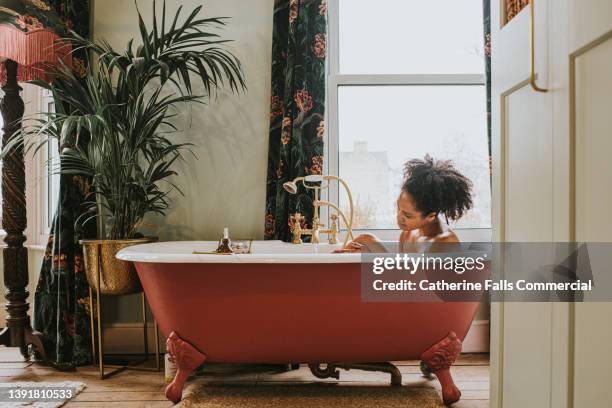 dreamy scene of a beautiful woman bathing in a roll top bathtub in a luxurious room - beautiful woman bath photos et images de collection