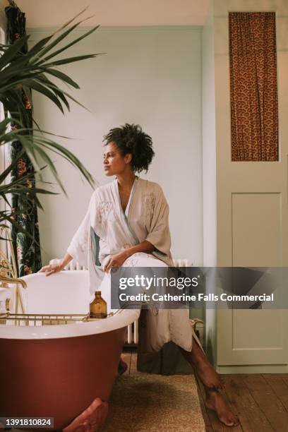 dreamy scene of a beautiful woman perching on the side of a roll top bathtub in a luxurious room - bathroom exercise stock pictures, royalty-free photos & images