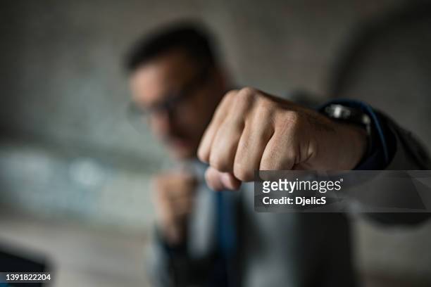 戦闘態勢のビジネスマンがパンチを仕掛ける。 - leadership fist ストックフォトと画像