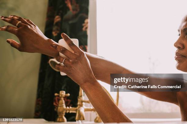 close-up of an elegant woman washing her arm with a bar of soap in the bath - barbade stock-fotos und bilder