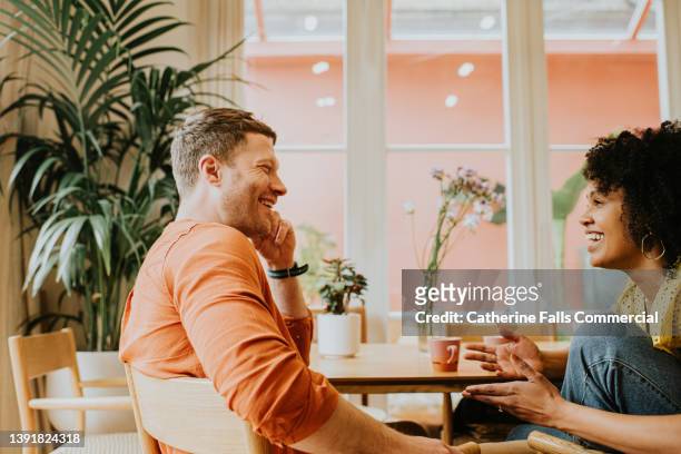 a man and a woman look relaxed as they have a lighthearted conversation. - nur erwachsene stock-fotos und bilder