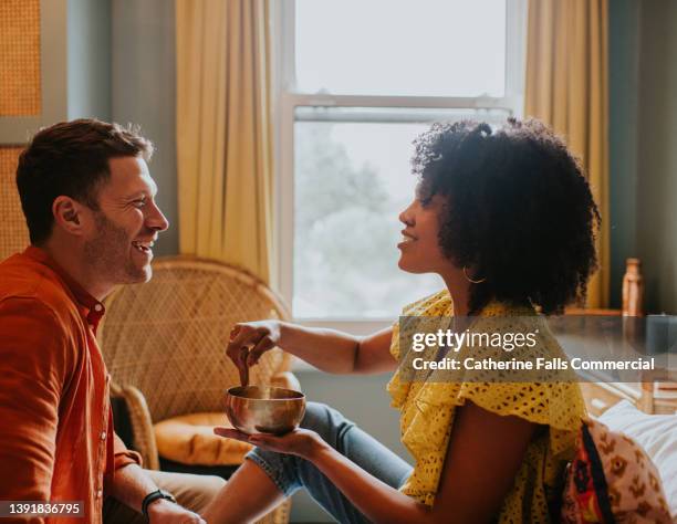 a woman shows her partner how a tibetan singing bowl works - 30 39 years stock pictures, royalty-free photos & images