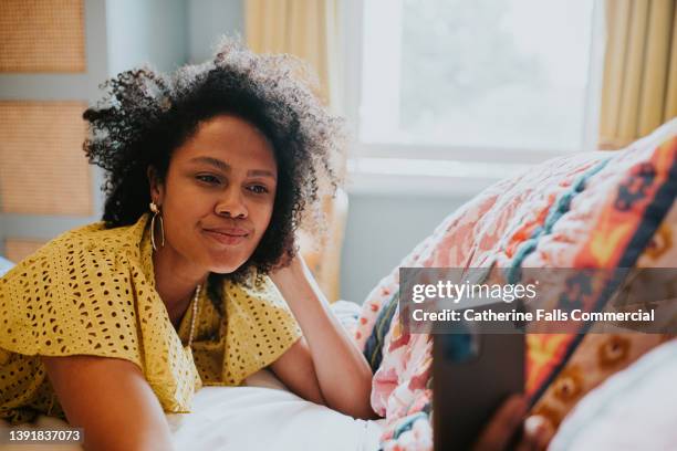 a beautiful woman poses as she takes a selfie of herself lying on a bed - weight gain stockfoto's en -beelden