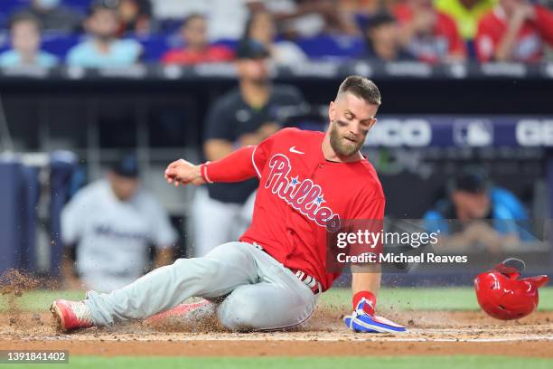 Bryce Harper of the Philadelphia Phillies safely slides home to score a run against the Miami Marlins during the second inning at loanDepot park on...