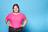 Young curvy latina woman smiling looking at camera isolated on turquoise background. Copy space.