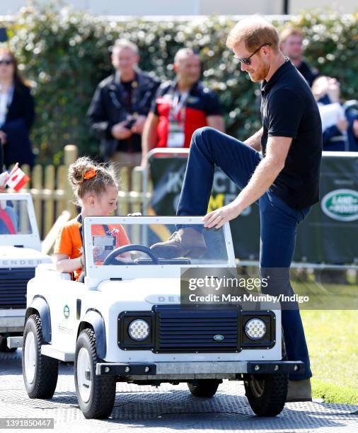 Prince Harry, Duke of Sussex accompanies a young girl as she drives a mini Land Rover Defender at the Land Rover Driving Challenge, on day 1 of the...