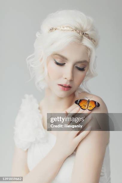 young blonde model in studio. woman with beautiful luxurious greek hairstyle in white dress. girl with butterfly on hand. golden wreath. albino. beauty portrait. greek goddess. purity and innocence - long bright yellow dress stock pictures, royalty-free photos & images