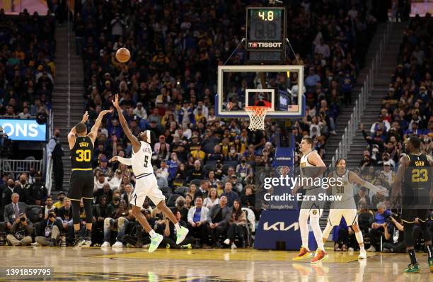 Stephen Curry of the Golden State Warriors shoots a three point basket over Will Barton of the Denver Nuggets at the end of the first half during...