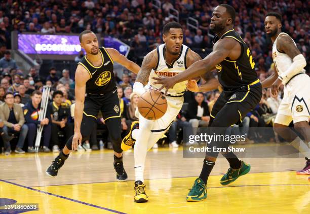 Monte Morris of the Denver Nuggets is guarded by Stephen Curry and Draymond Green of the Golden State Warriors in the first half during Game One of...