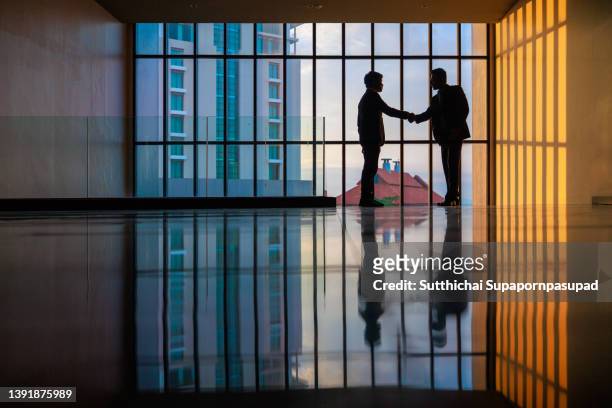 the shot of two businessman making a successful business with shaking hand. - handshake business zwei personen stock-fotos und bilder