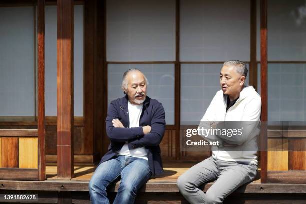 two senior males sitting on porch of old traditional japanese house - washitsu stock pictures, royalty-free photos & images