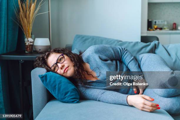 middle age woman lying on sofa and feel abdomen pain - stomachache fotografías e imágenes de stock