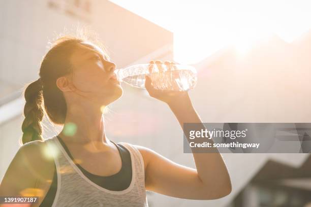 nahaufnahme einer asiatischen frau, die nach dem training wasser trinkt - woman drinking water from bottle stock-fotos und bilder